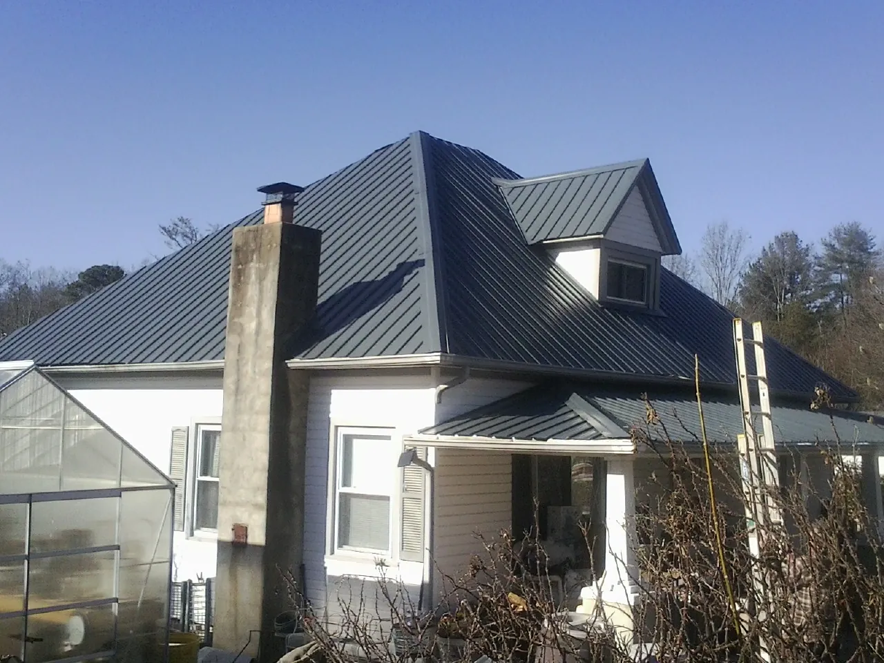 Dark blue standing seam metal roof on a white farmhouse with dormer — Slate & Tile Roof Repair by Roofing Brothers in Penn Laird
