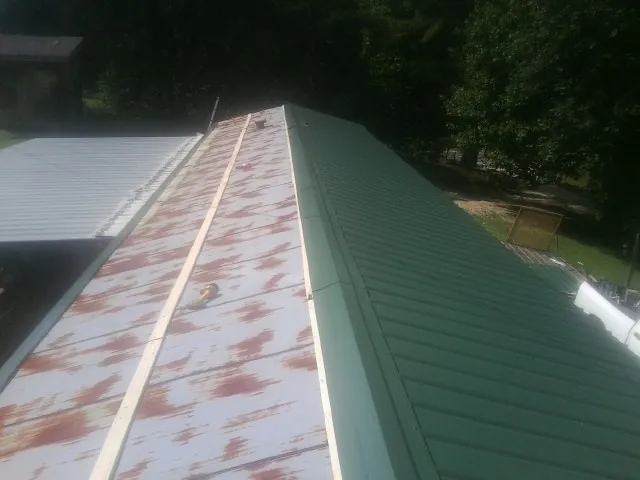 Old rusted panels beside newly installed green metal roofing — Wind Damage Roof Repair by Roofing Brothers in Penn Laird