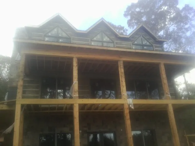 Dormers and porch framing on a large log home under construction — Roof Coating work by our crew in Penn Laird