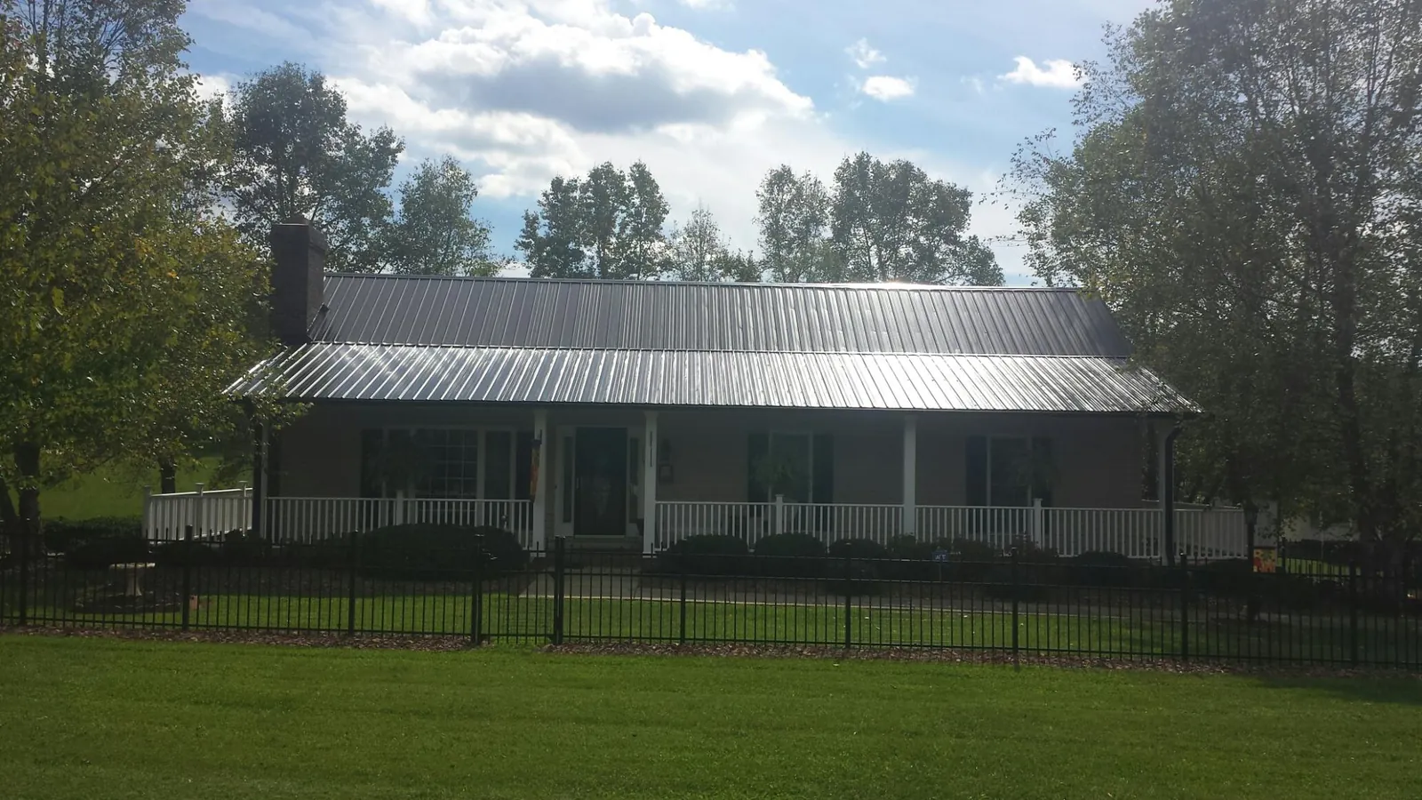 Gray metal roof on a brick ranch with a full width front porch — Gutter Guard Installation work by our crew in Penn Laird
