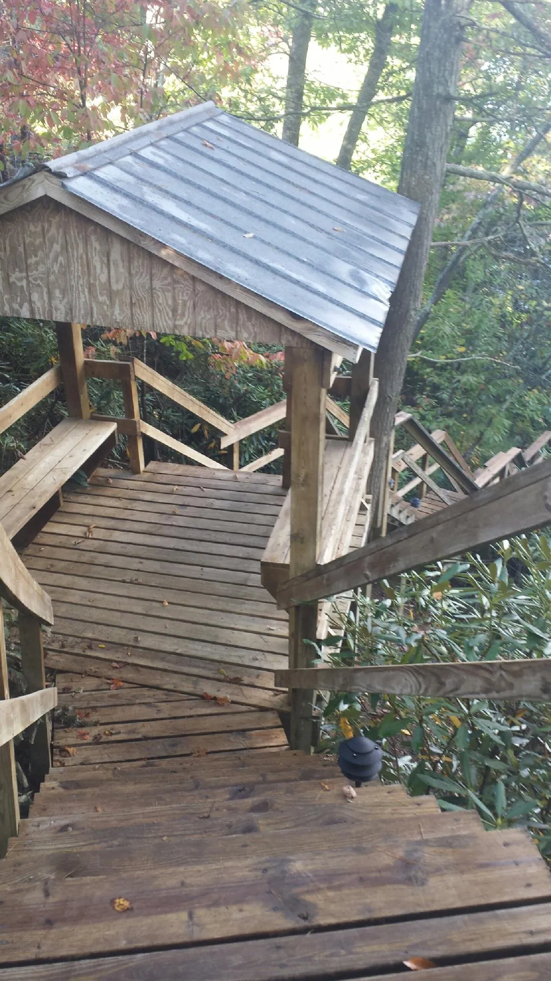 Metal roofed shelter over wooden steps on a wooded walkway — Skylight Repair & Installation work by our crew in Penn Laird