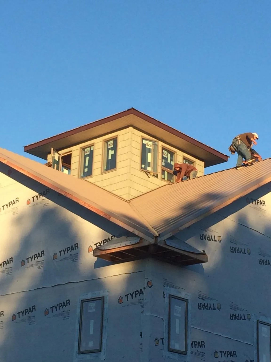 Roofers working around a rooftop cupola on a new metal roof at sunset — Roof Waterproofing in Penn Laird by Roofing Brothers